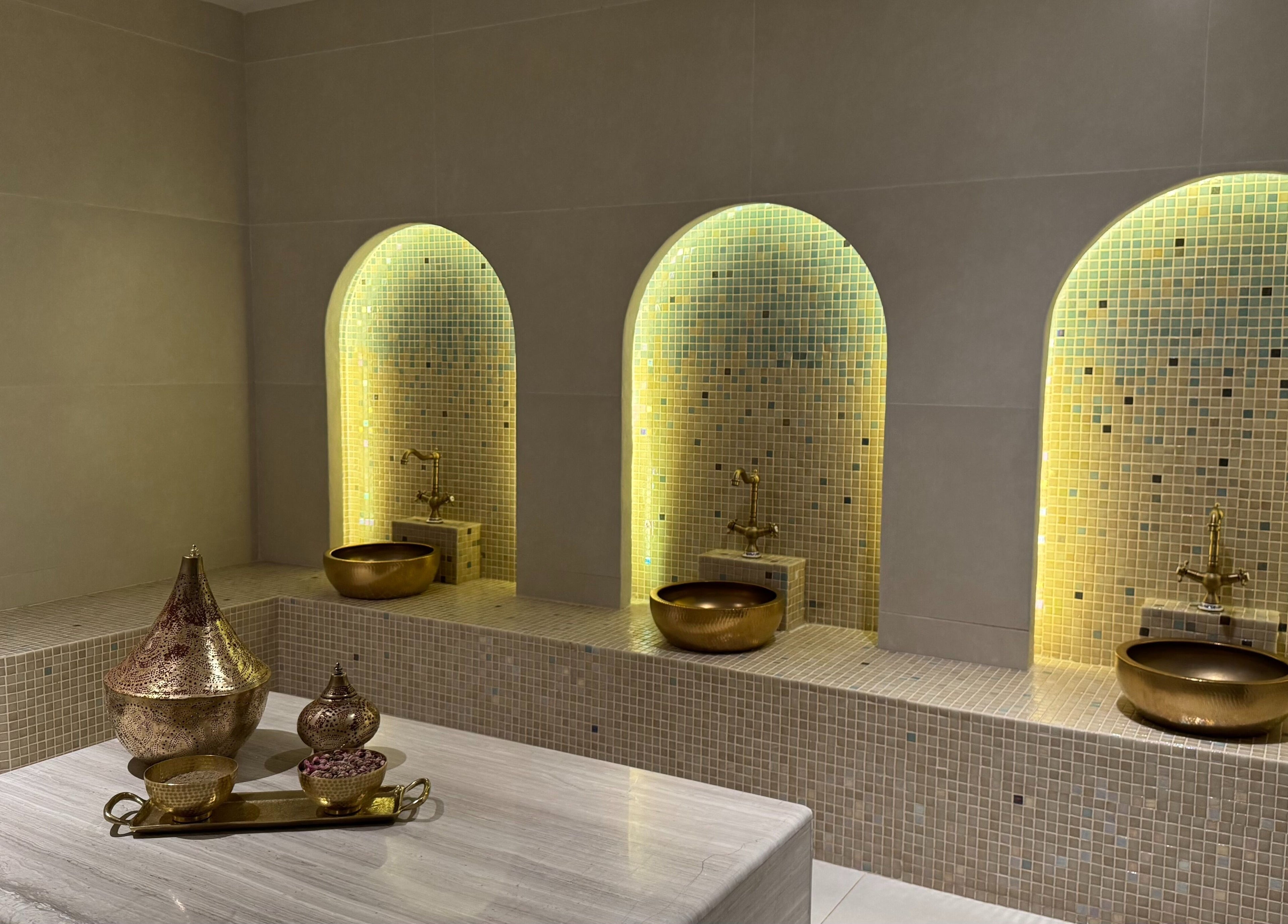 Luxurious spa room at MYB Lounge & Spa, Al Khobar, Eastern Province, SA with golden basins and ambient lighting.