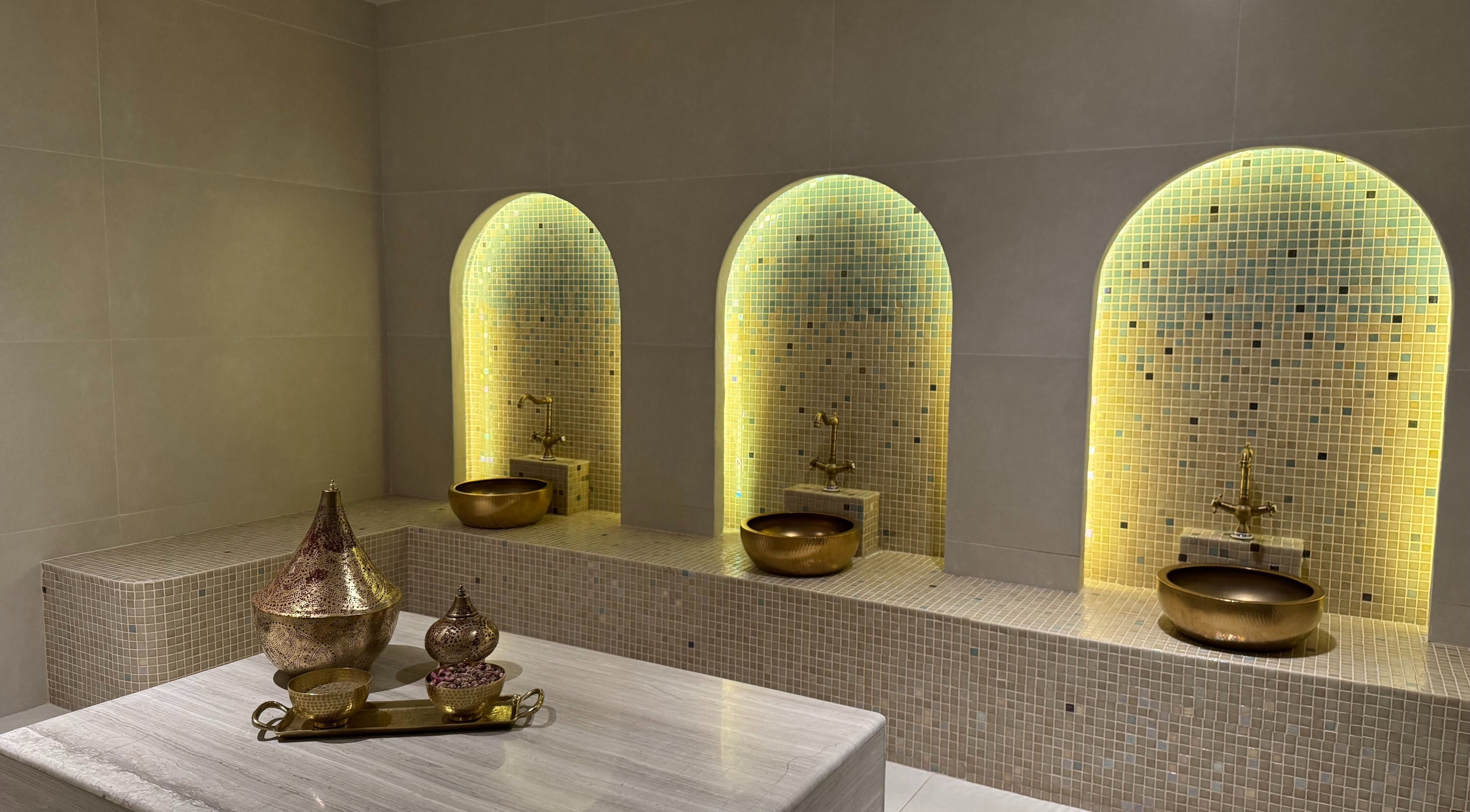 Luxurious spa room at MYB Lounge & Spa, Al Khobar, Eastern Province, SA with golden basins and ambient lighting.