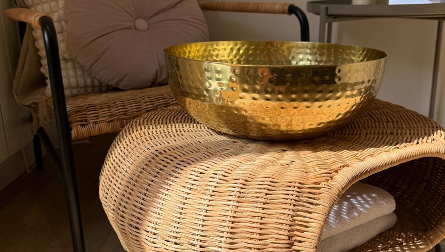 Golden bowl on wicker chair at ML BEAU-TY, Waterlooville, England, GB enhancing a serene ambiance.