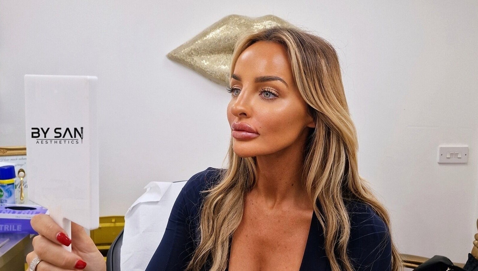 Woman admiring her look in a mirror at By San Aesthetics, Telford, England, GB.