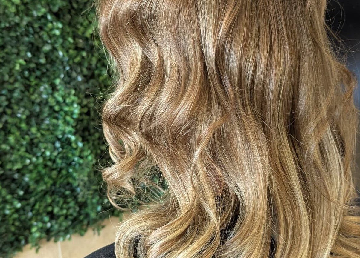 Elegant wavy blonde hair styled at Bex at Lillywhite & Co., Wakefield, England, GB with a lush background.
