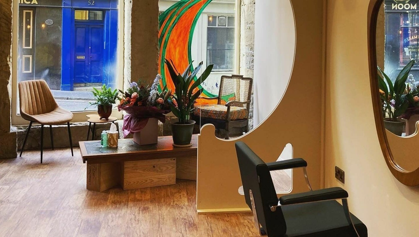 Stylish interior of Outline Hair in Edinburgh, Scotland, GB with a modern chair and plants.