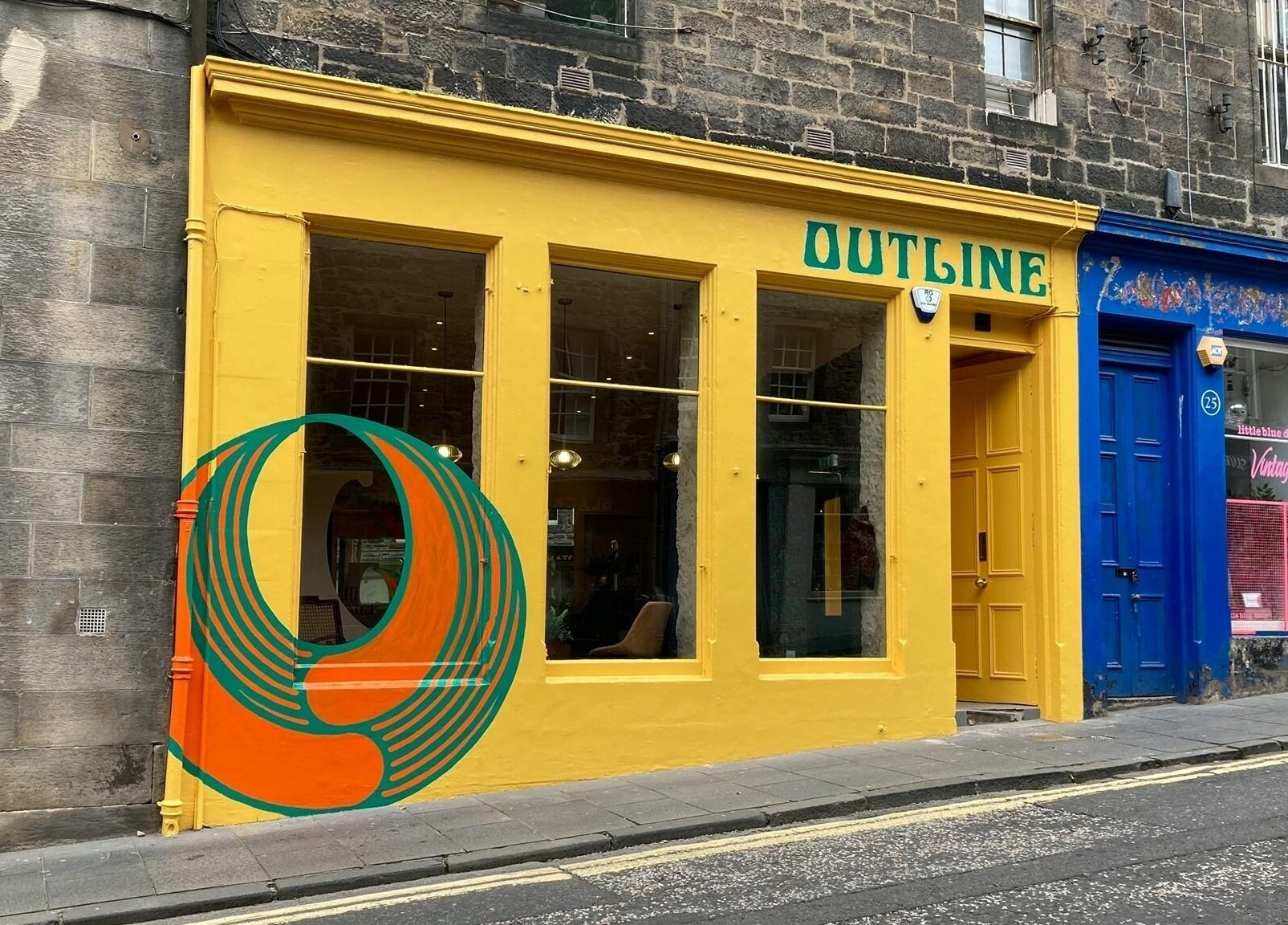 Colorful entrance of Outline Hair in Edinburgh, Scotland, GB, featuring a bold mural and yellow door.