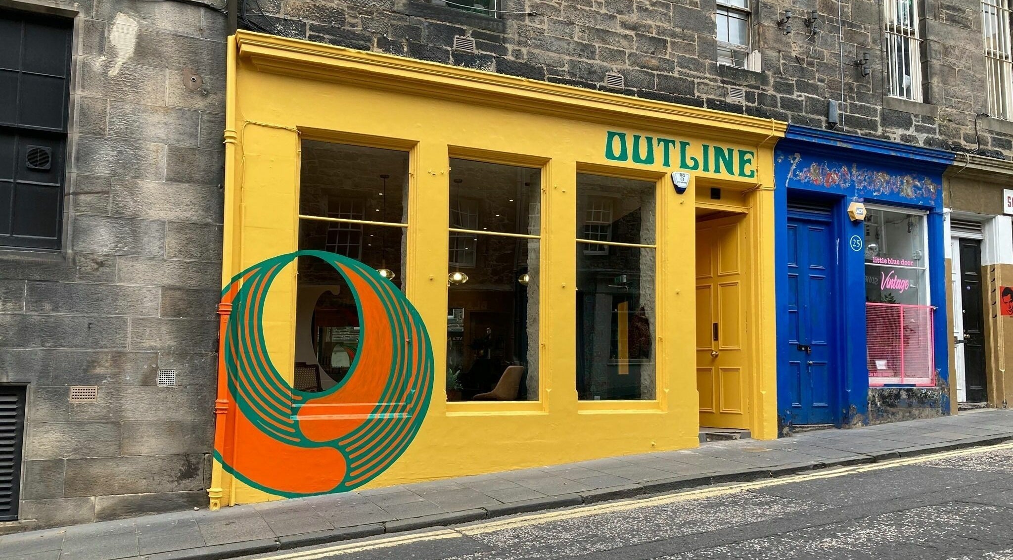 Colorful entrance of Outline Hair in Edinburgh, Scotland, GB, featuring a bold mural and yellow door.