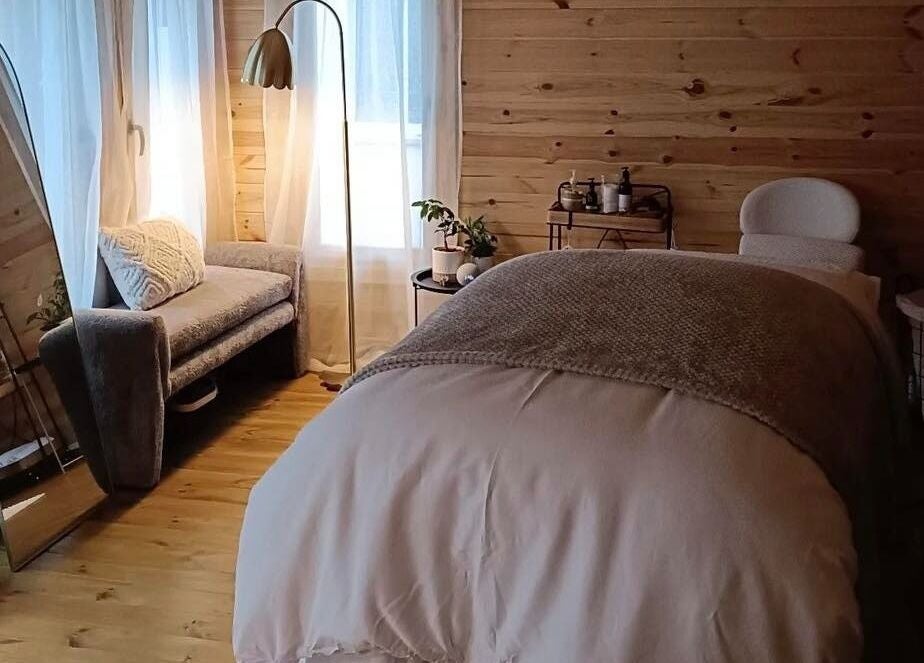 Cozy massage room at Ruska, Poole, England, GB with natural wood decor and soft lighting.