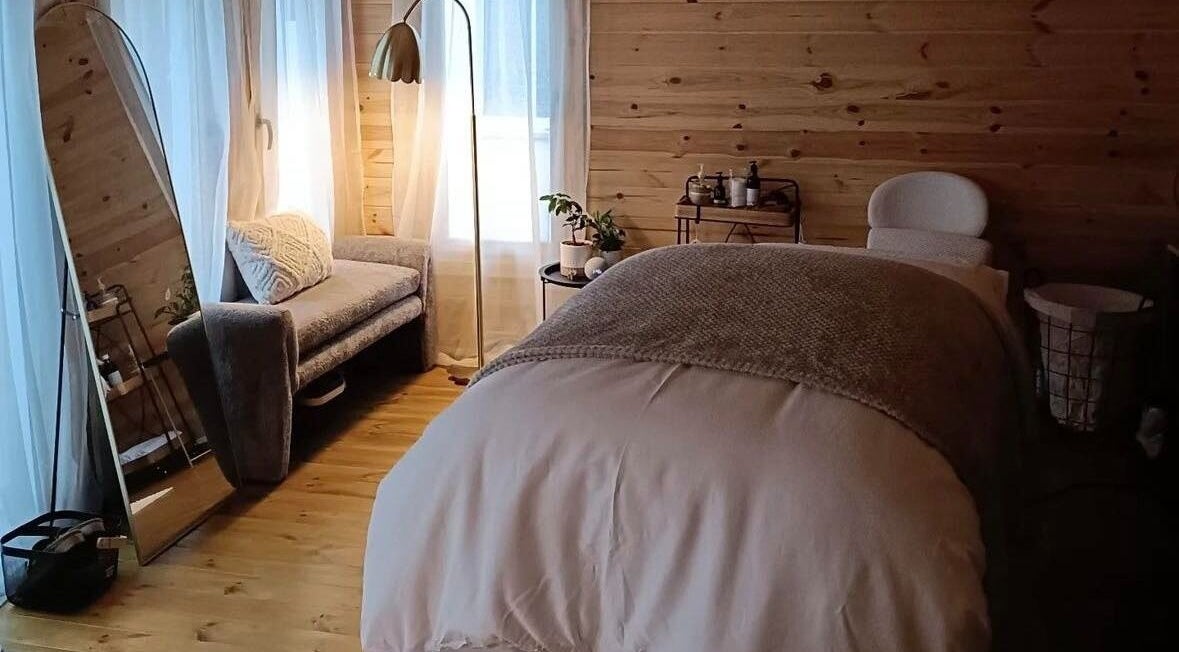 Cozy massage room at Ruska, Poole, England, GB with natural wood decor and soft lighting.