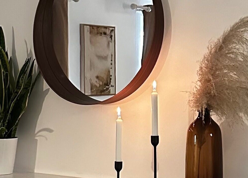 Elegant decor setup at Ruska, Poole, England, GB with a round mirror, candles, and pampas grass.