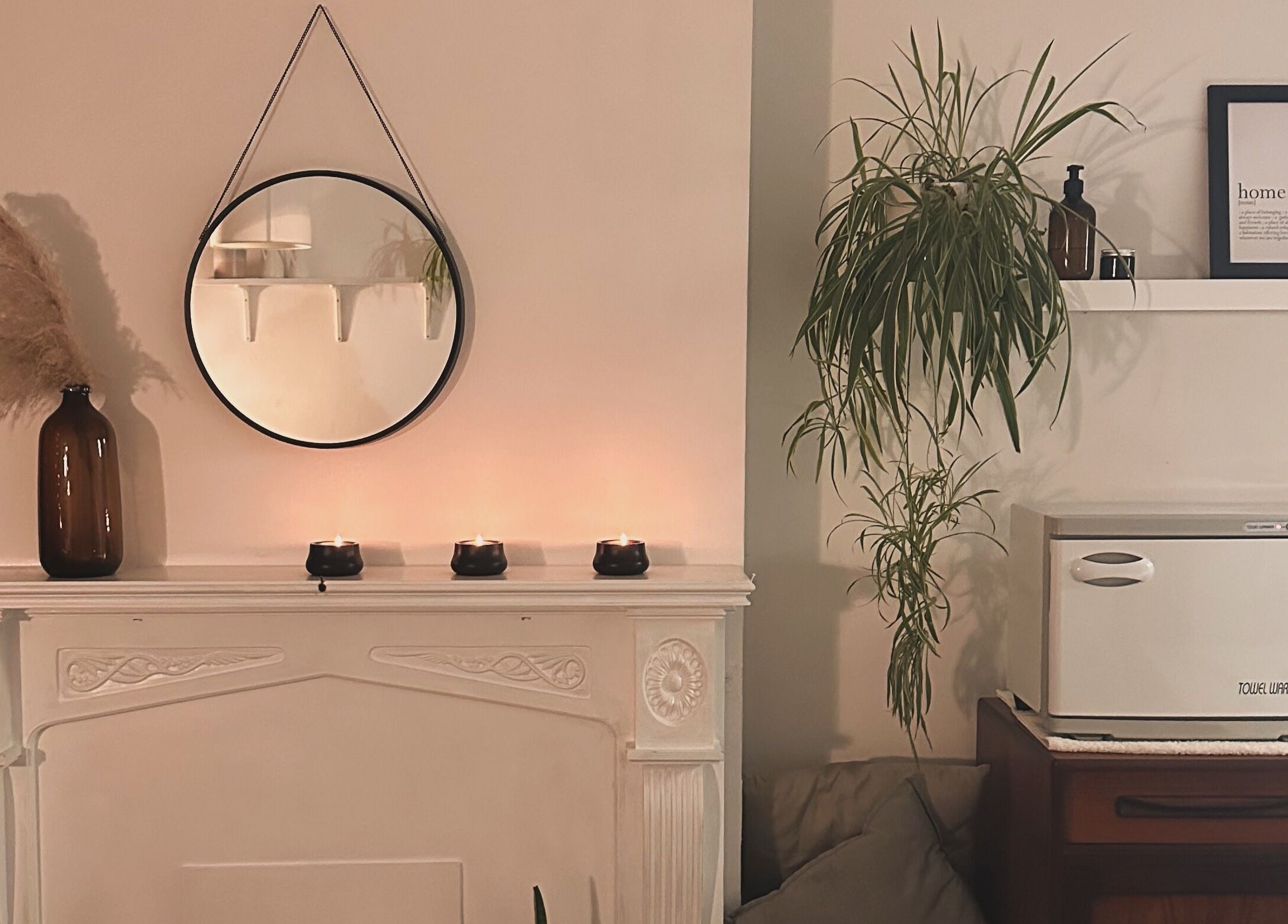 Cozy wellness space at Ruska, Poole, England, GB, featuring a round mirror, candles, and lush plants.