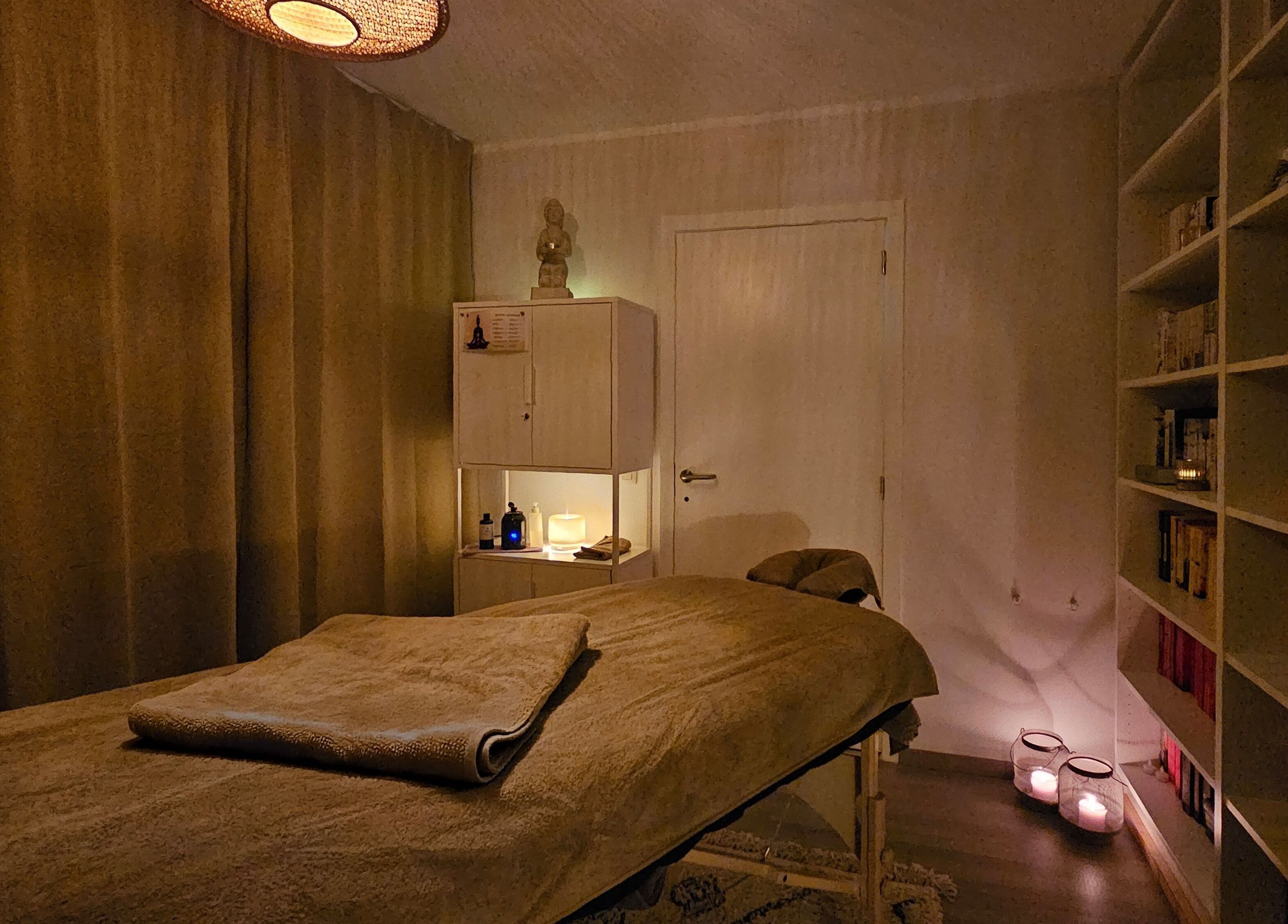 Rustieke massageruimte in Levensrust, Kortrijk, Vlaams Gewest, BE met warme verlichting en boekenplank.
