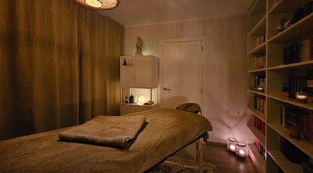 Rustieke massageruimte in Levensrust, Kortrijk, Vlaams Gewest, BE met warme verlichting en boekenplank.