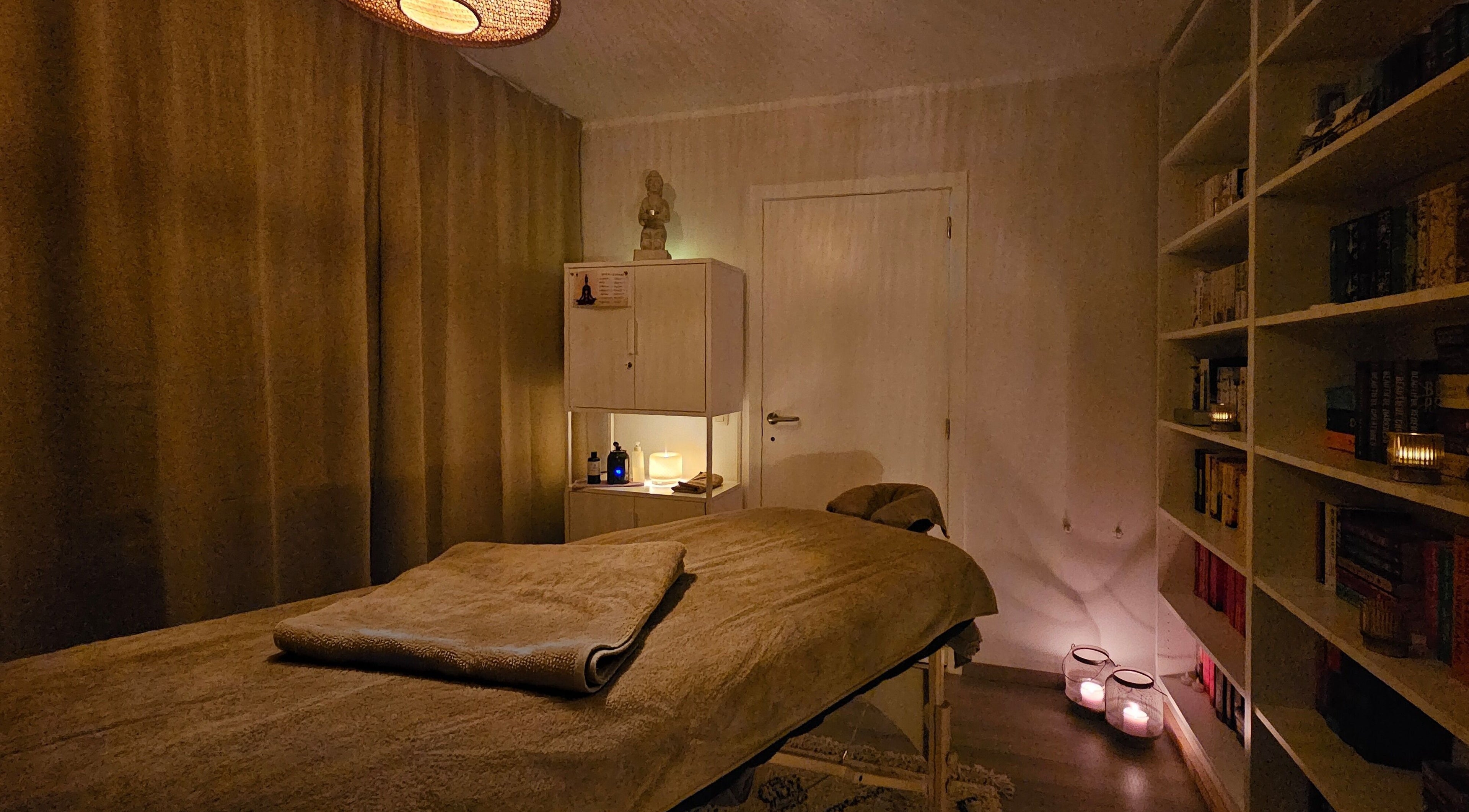 Rustieke massageruimte in Levensrust, Kortrijk, Vlaams Gewest, BE met warme verlichting en boekenplank.