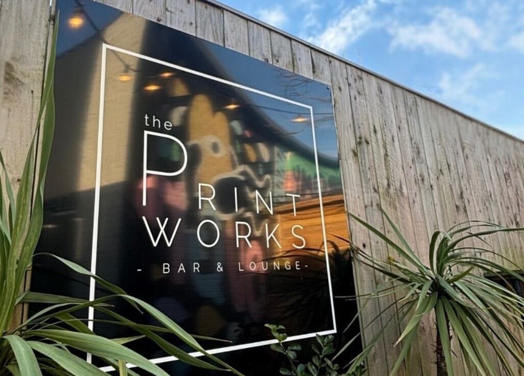 Elegant sign on wooden fence at By Layla Jayne, Newcastle upon Tyne, England, GB, surrounded by lush green plants.