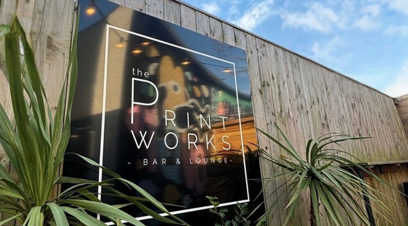 Elegant sign on wooden fence at By Layla Jayne, Newcastle upon Tyne, England, GB, surrounded by lush green plants.