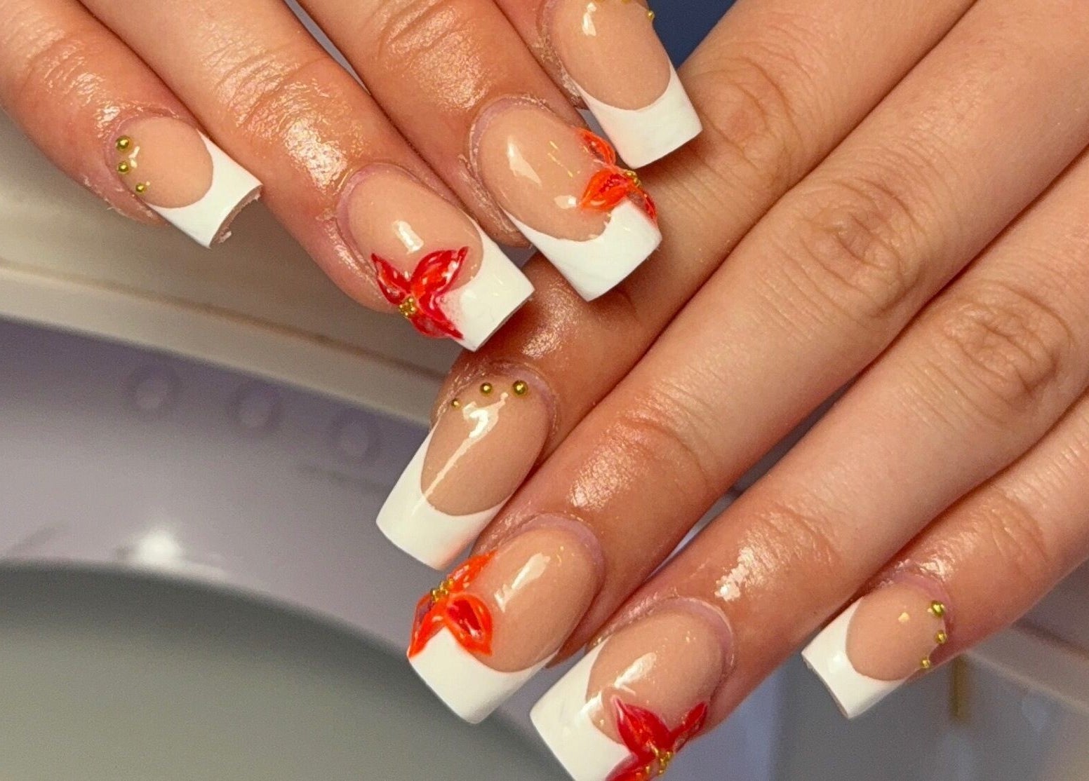 Elegant floral nail art with orange accents by Layla Jayne, located in Newcastle upon Tyne, England, GB.