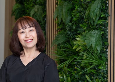 A welcoming staff member at Disara Thai Massage in Las Vegas, Nevada, US, standing before a lush green backdrop.