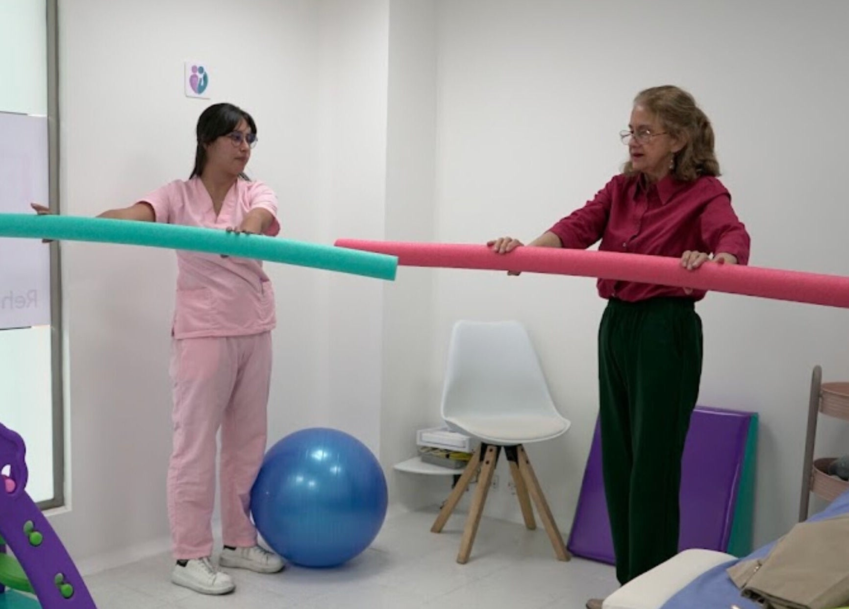 Terapia en Fono-Care, Bogotá. Dos personas usando barras de espuma en actividades de bienestar.