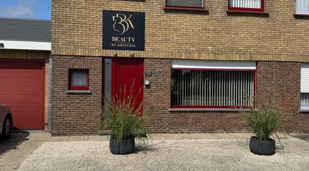Voorgevel van Beauty by Kristina, Gistel, Vlaams Gewest, BE met rode deur en planten.