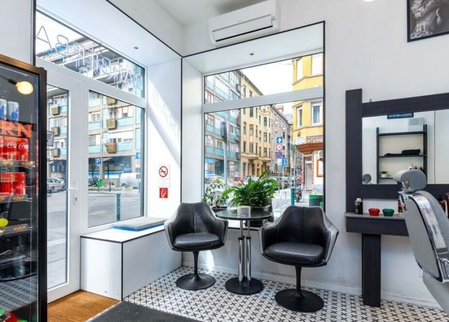 Belvárosi szalon ülősarok a BarberBar-ban, Budapest, Magyar, HU. Stílusos fekete székek és növények.