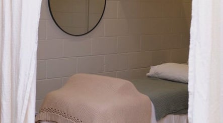Cozy treatment room in yourSPAce, Christchurch, Canterbury Region, NZ, featuring a blanket-covered bed and round mirror.