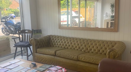 Cozy seating area at The Massage Space, Winchester, England, GB with green sofa and large mirror.