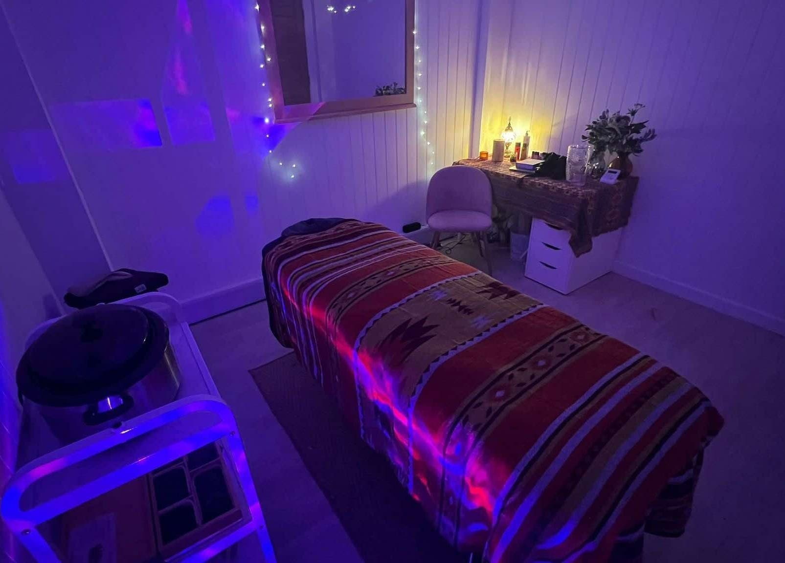Dimly lit massage room in The Massage Space, Winchester, England, GB with a decorated bed and calming lights.