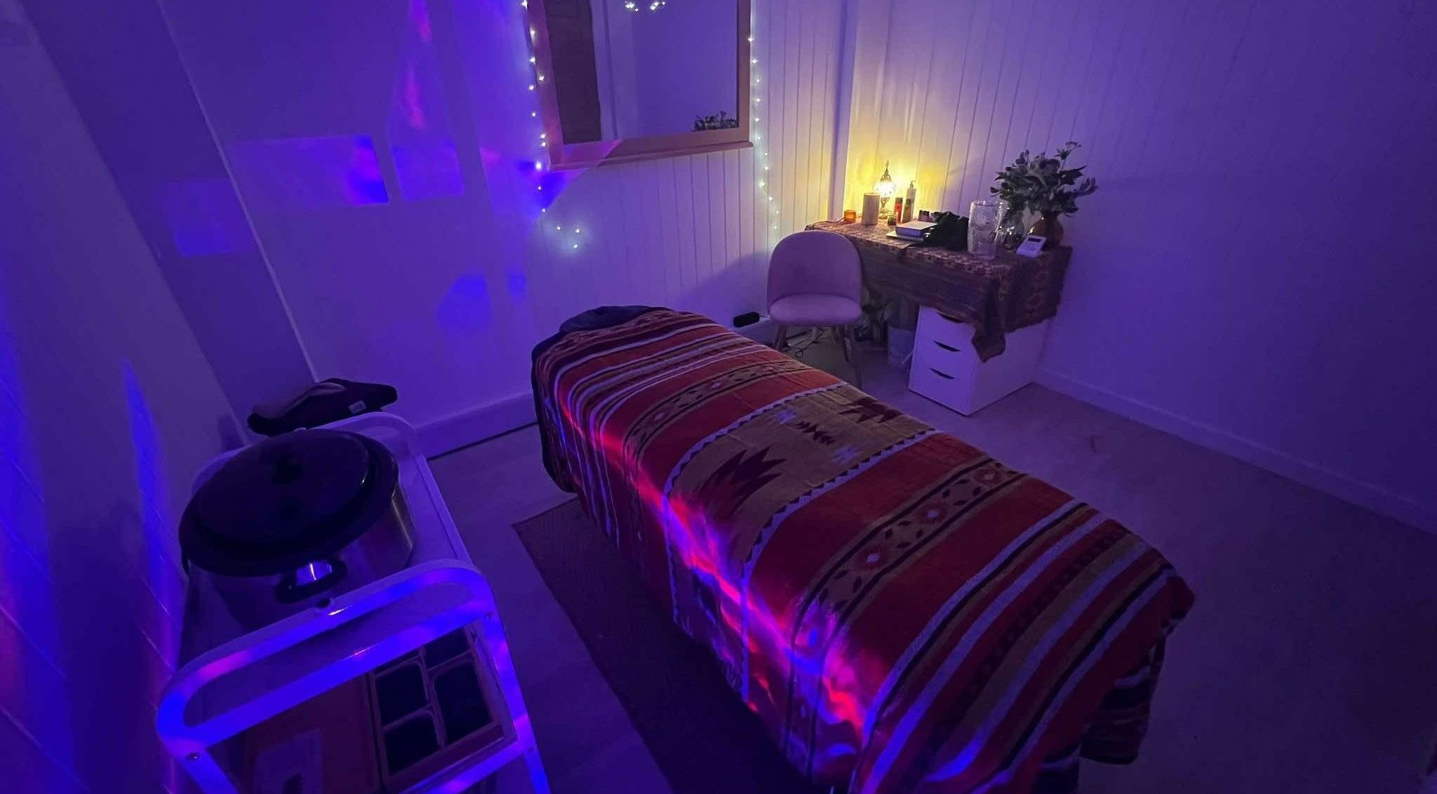 Dimly lit massage room in The Massage Space, Winchester, England, GB with a decorated bed and calming lights.