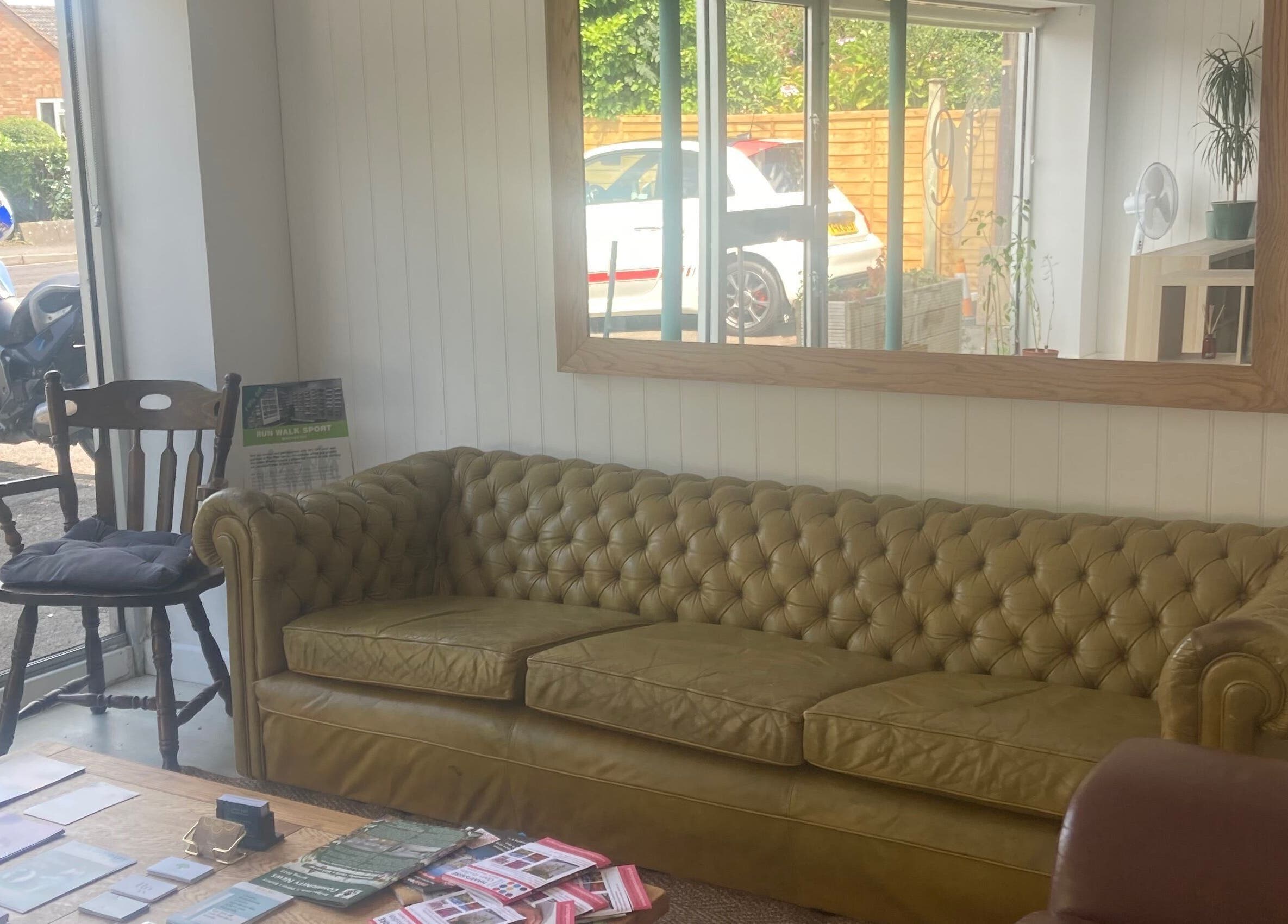Charming waiting area at The Massage Space, Winchester, England with a comfy sofa and window view.