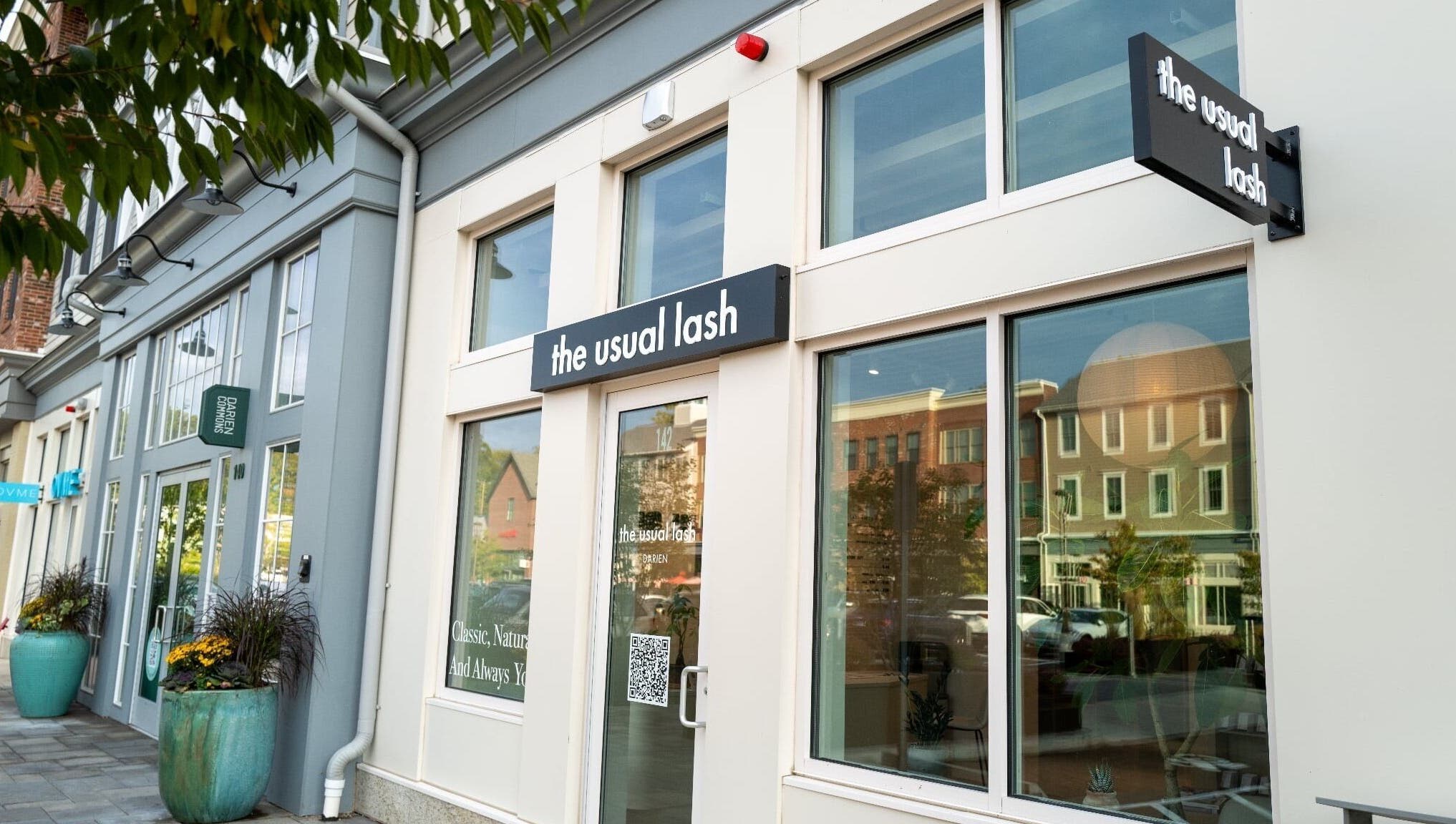 Exterior view of The Usual Lash in Darien, Connecticut, US, featuring elegant signage and large windows.