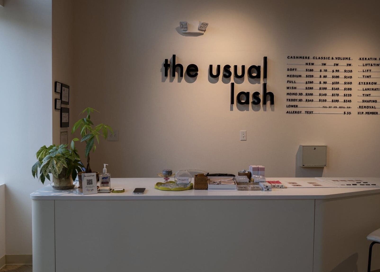 Reception area of The Usual Lash in Darien, Connecticut, US, featuring sleek decor and informative signage.