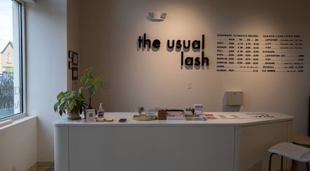 Reception area of The Usual Lash in Darien, Connecticut, US, featuring sleek decor and informative signage.