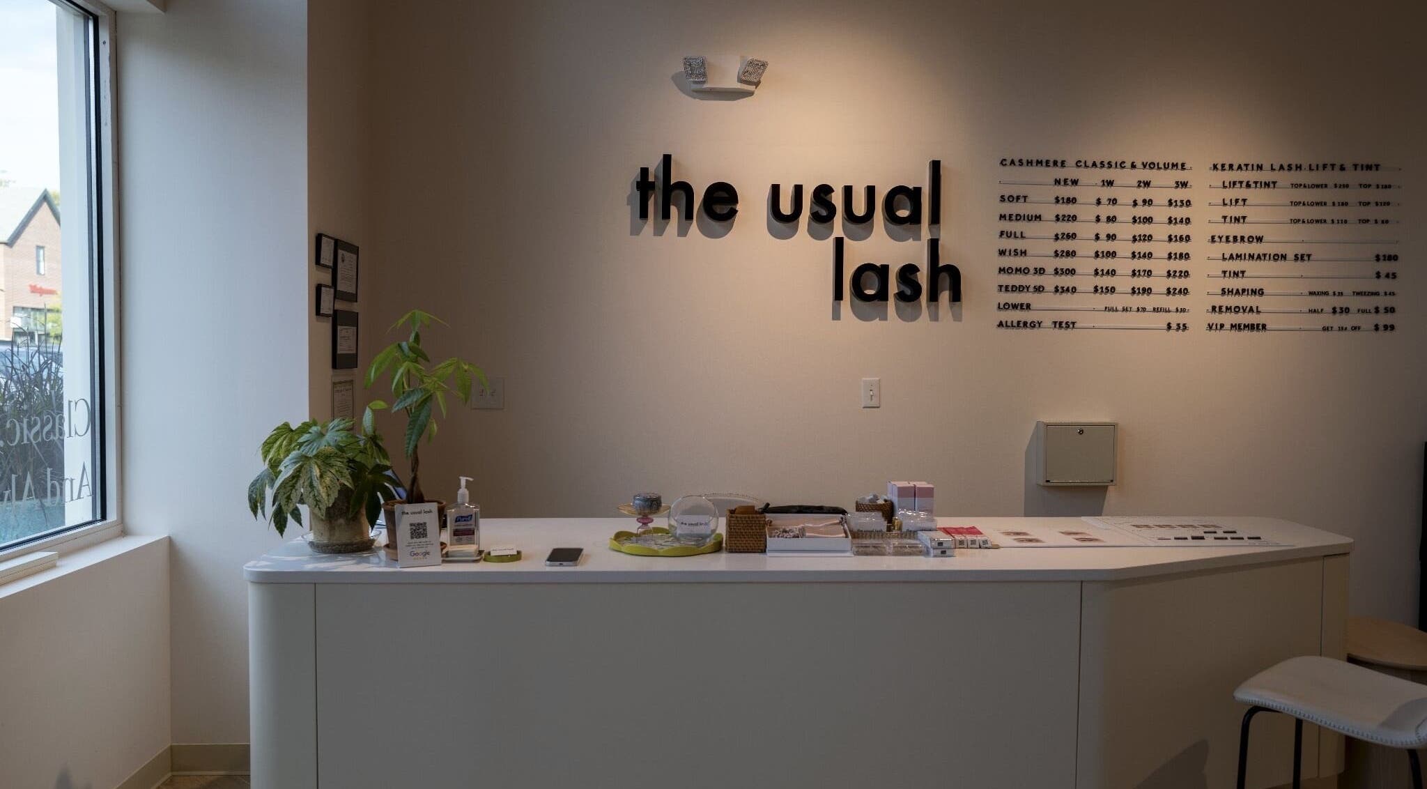 Reception area of The Usual Lash in Darien, Connecticut, US, featuring sleek decor and informative signage.