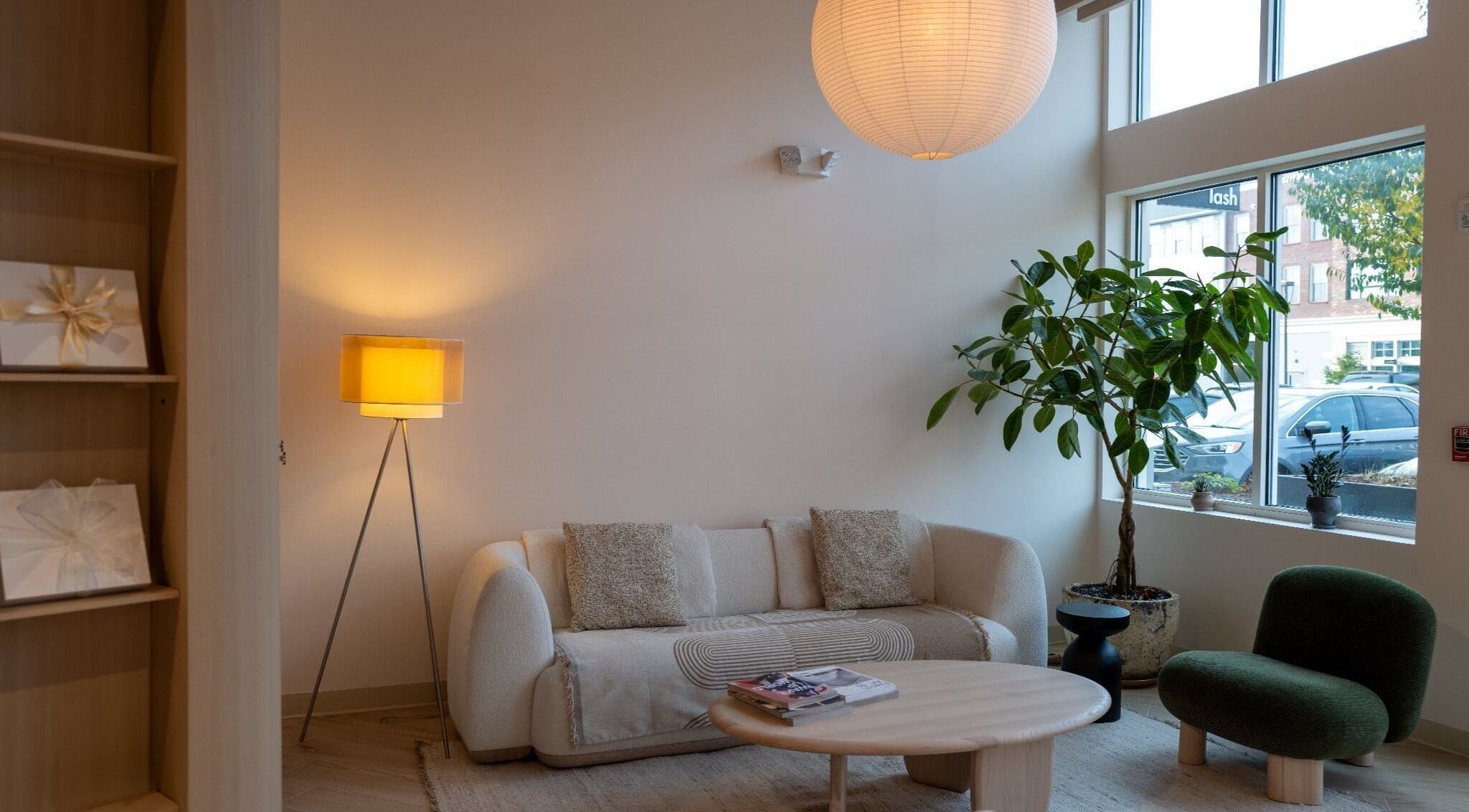 Bright lounge at The Usual Lash, Darien, Connecticut, US, featuring a modern sofa and large window.