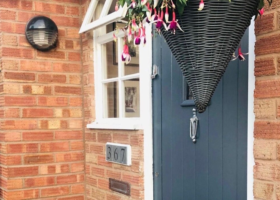 Welcoming entrance of Apple Lodge Therapies in Redditch, England, GB with blue door and hanging basket.