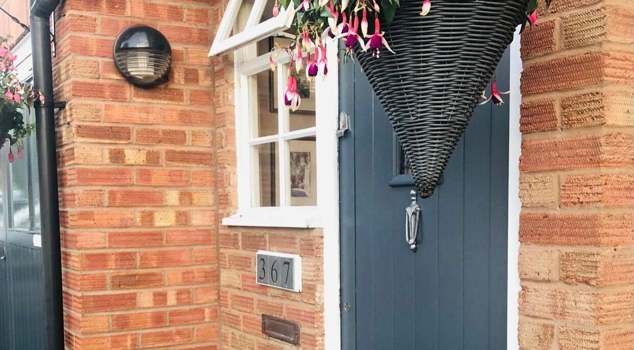 Welcoming entrance of Apple Lodge Therapies in Redditch, England, GB with blue door and hanging basket.