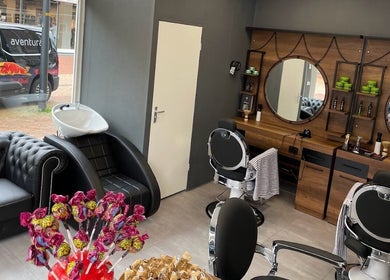Gezellige salonruimte van Ilyana Kapsalon in Drachten, Friesland, NL met zwarte meubels en spiegels.