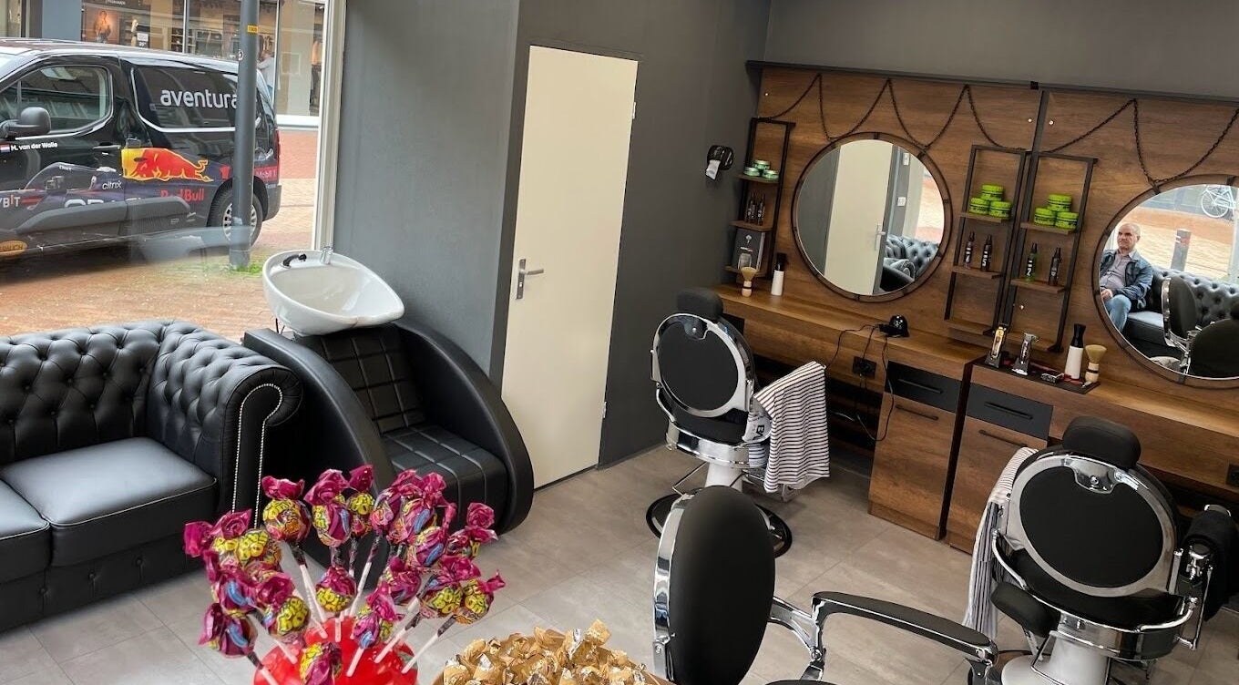 Gezellige salonruimte van Ilyana Kapsalon in Drachten, Friesland, NL met zwarte meubels en spiegels.