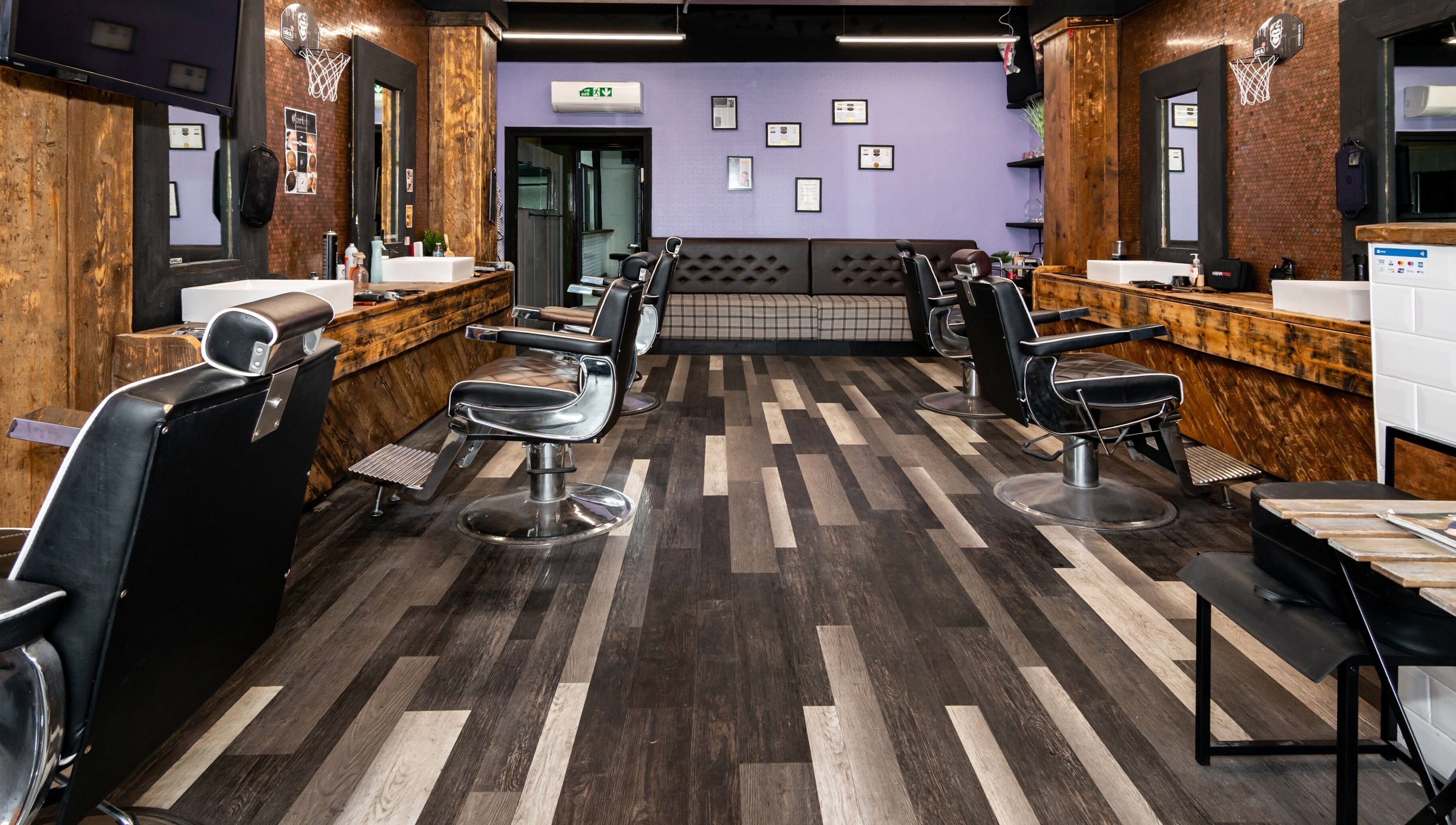 Modern interior of Skins & Needles Barbers in Middlesbrough, England featuring sleek black chairs and wood accents.