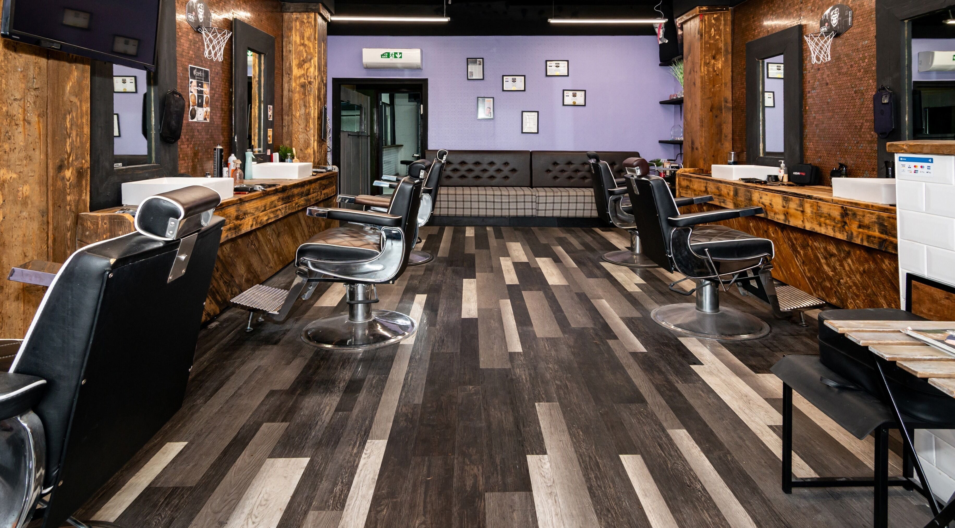 Modern interior of Skins & Needles Barbers in Middlesbrough, England featuring sleek black chairs and wood accents.