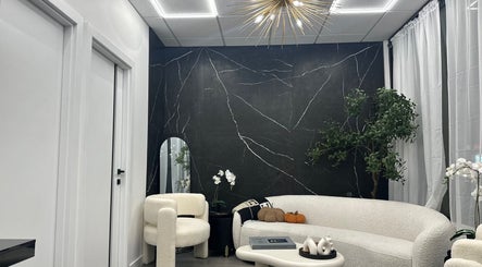 Modern lounge area at ELEVATE, Bellmore, New York, US, featuring elegant white seating and dark marble wall.