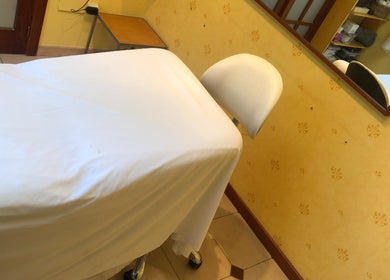 Sala de tratamiento en Cris Falcão Beauty PMU, Cambrils, Cataluña, ES, equipada con cama y decoración cálida.