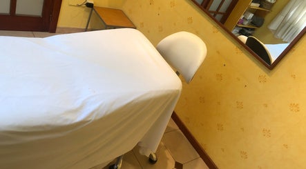 Sala de tratamiento en Cris Falcão Beauty PMU, Cambrils, Cataluña, ES, equipada con cama y decoración cálida.