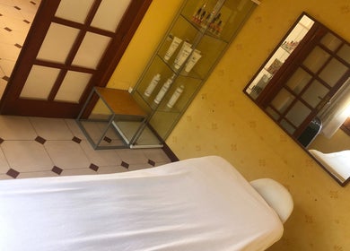 Sala de tratamiento relajante en Cris Falcão Beauty PMU, Cambrils, Cataluña, ES, con cama y estantería elegante.
