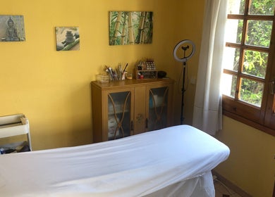 Sala de tratamiento en Cris Falcão Beauty PMU, Cambrils, Cataluña, ES, con cama de masaje y luz natural.