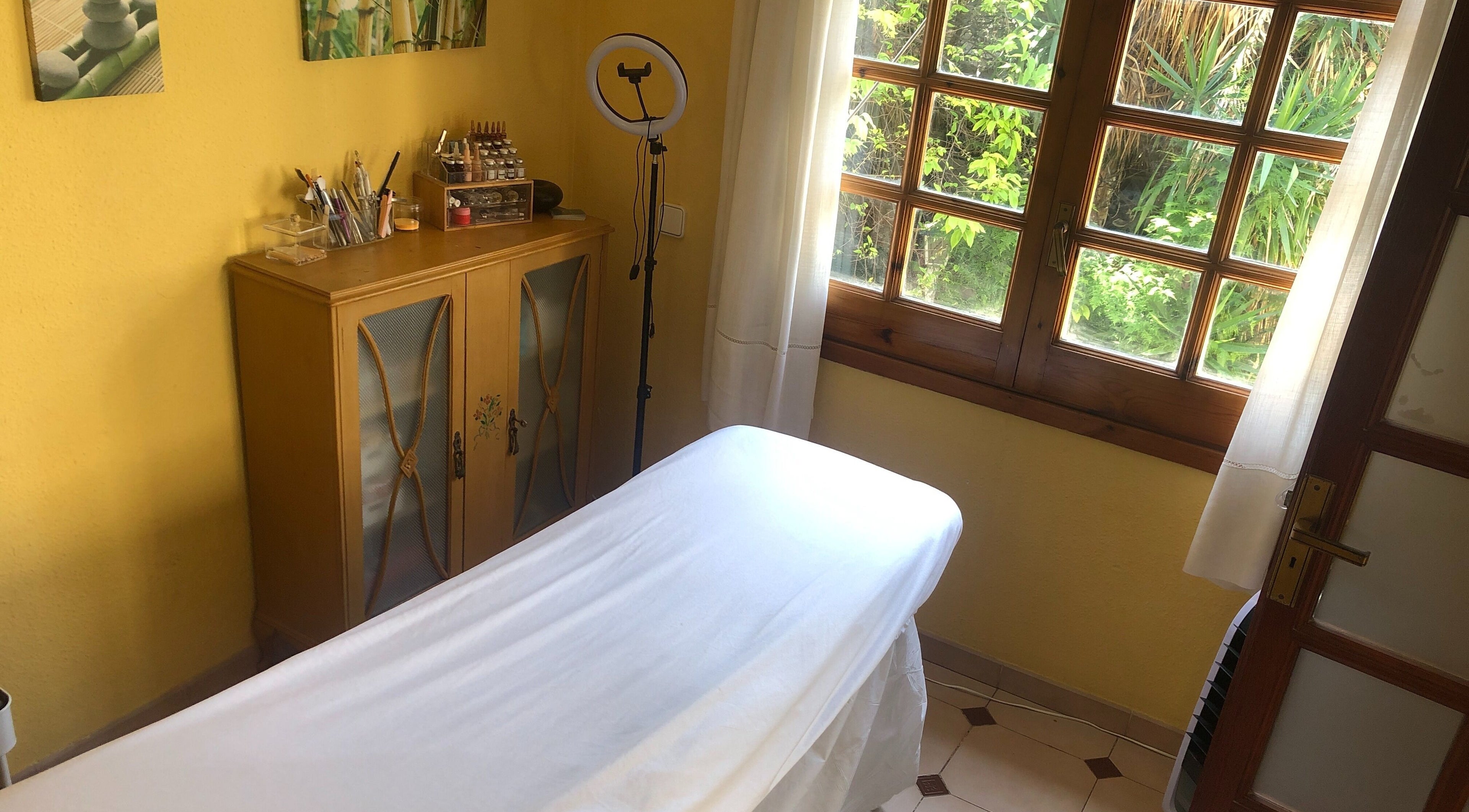 Sala de tratamiento en Cris Falcão Beauty PMU, Cambrils, Cataluña, ES con luz natural y decoración acogedora.