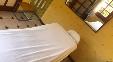 Sala de tratamiento en Cris Falcão Beauty PMU, Cambrils, Cataluña, ES, vista de cama con espejo y ventana.