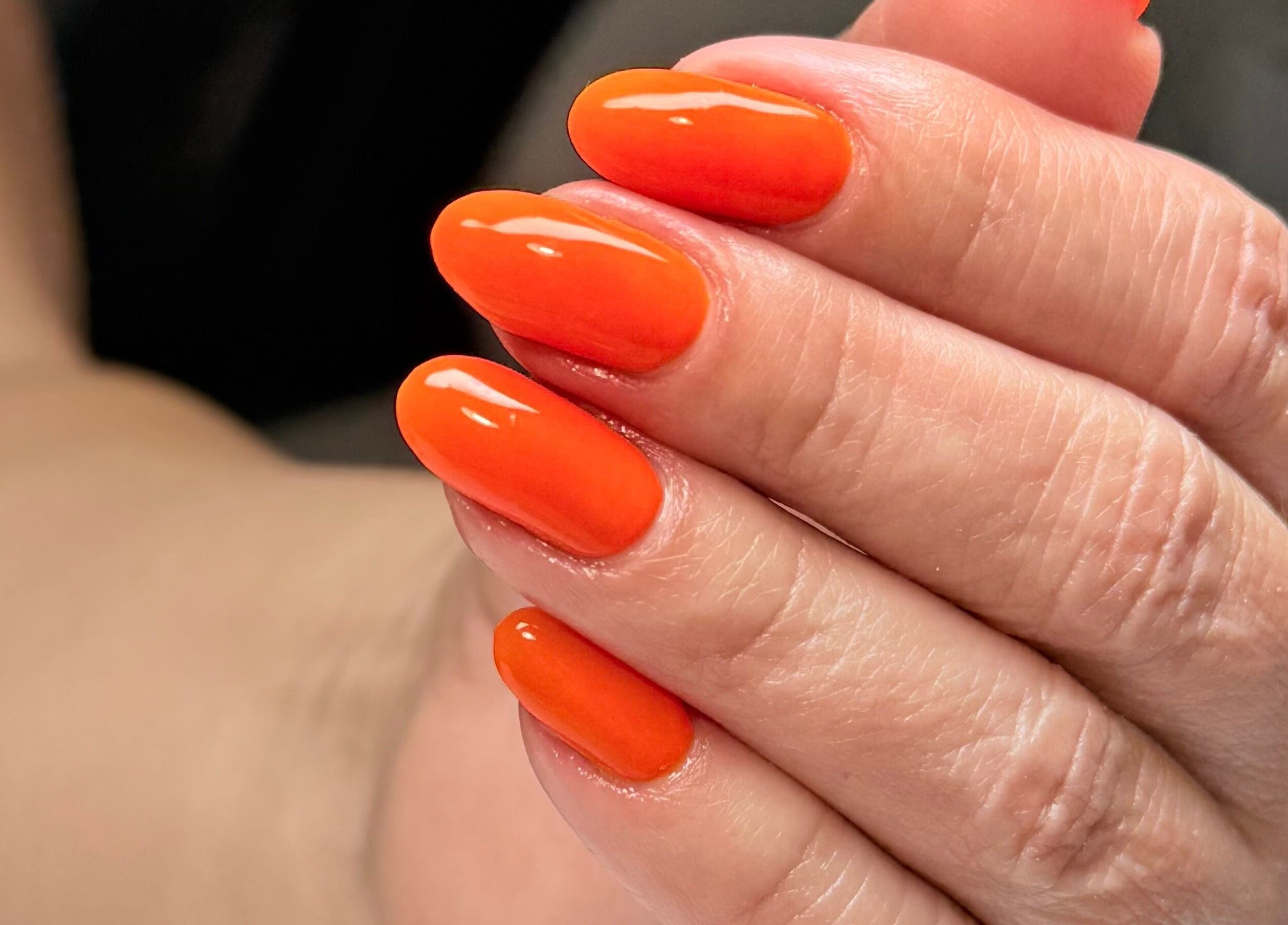 Uñas con esmalte naranja vibrante en Jasmin Nails Artist, Hialeah, Florida, US.