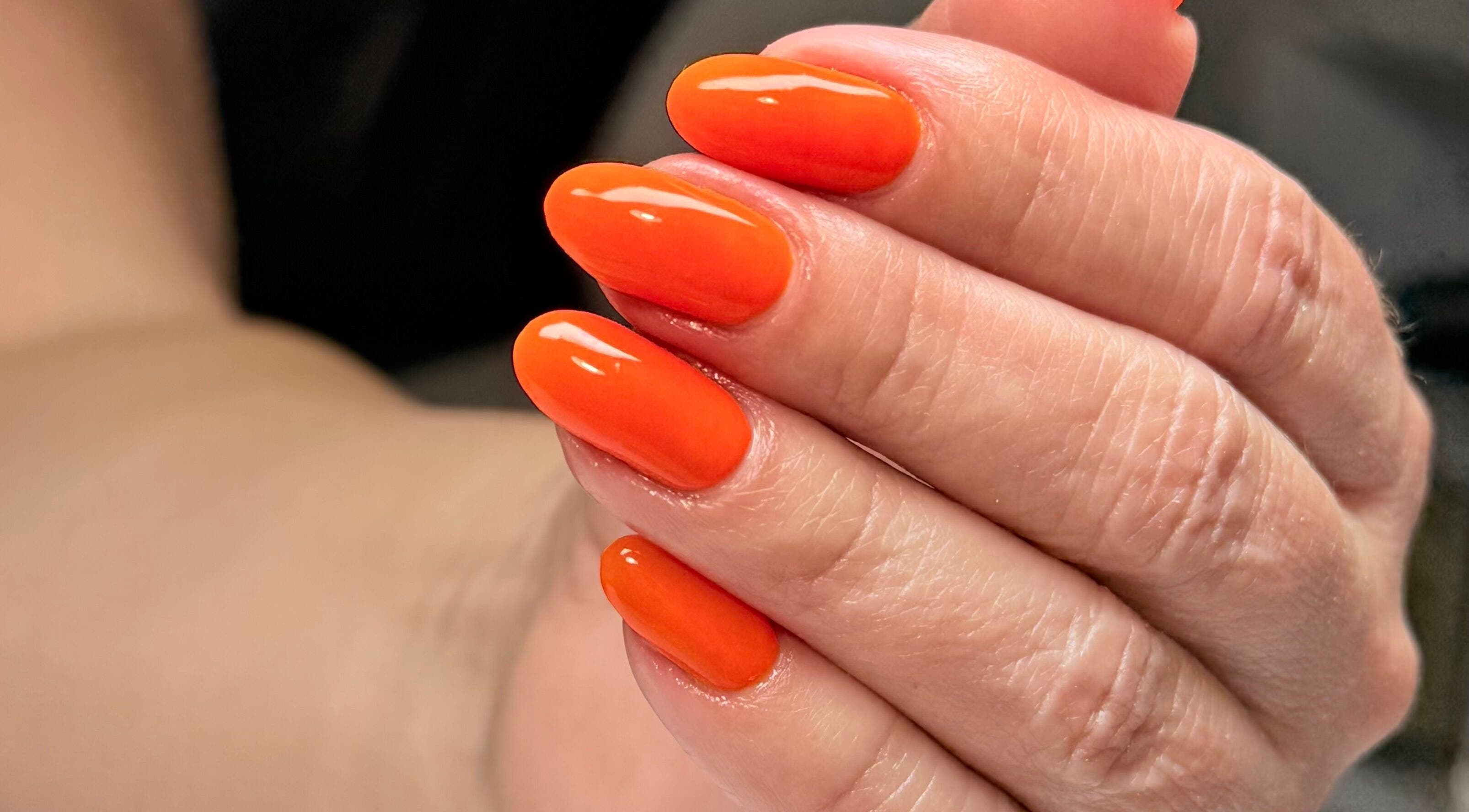 Uñas con esmalte naranja vibrante en Jasmin Nails Artist, Hialeah, Florida, US.
