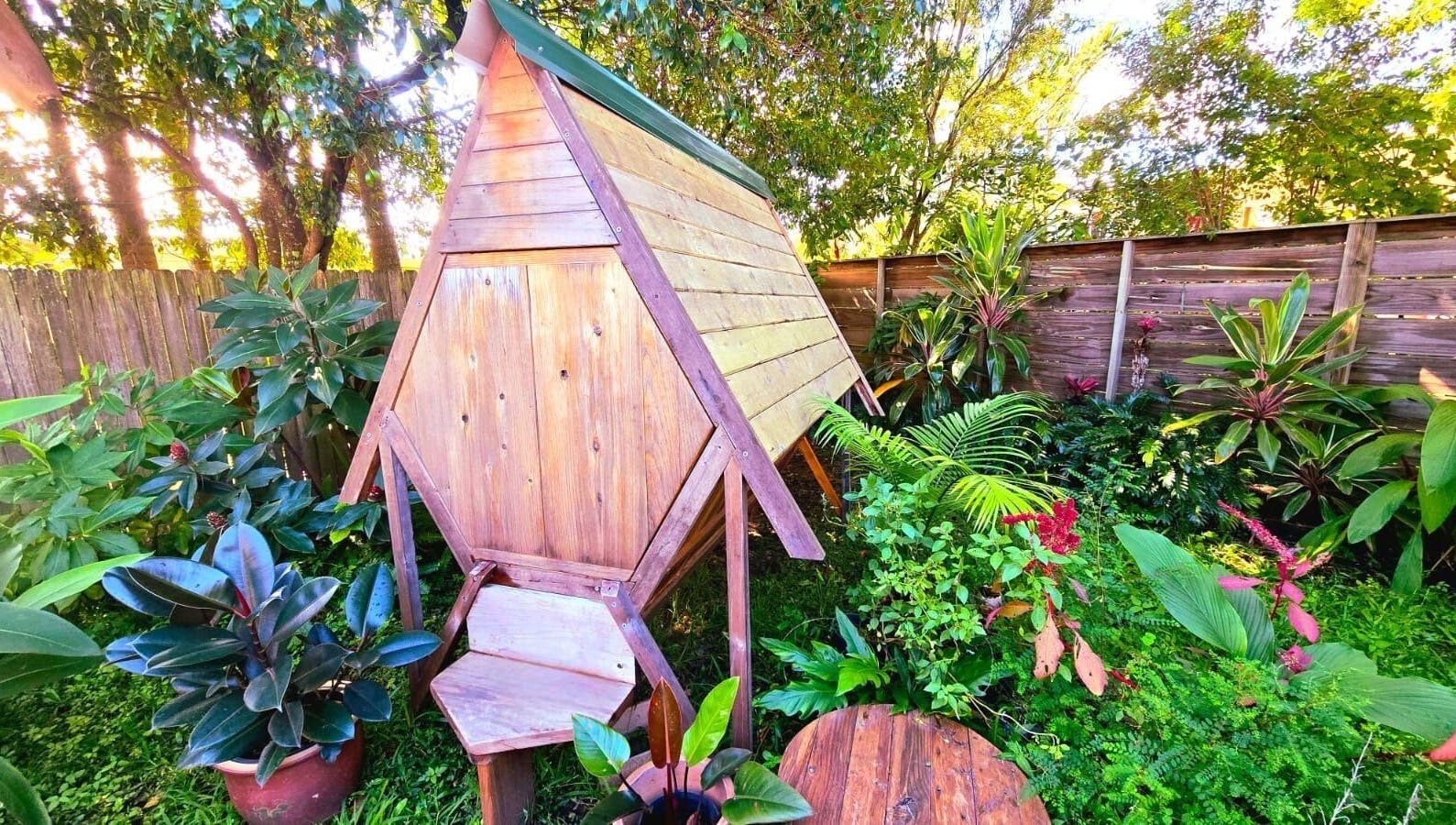 Serene garden view at Bee Alive, Mullumbimby, New South Wales, AU, featuring lush greenery and wooden structure.