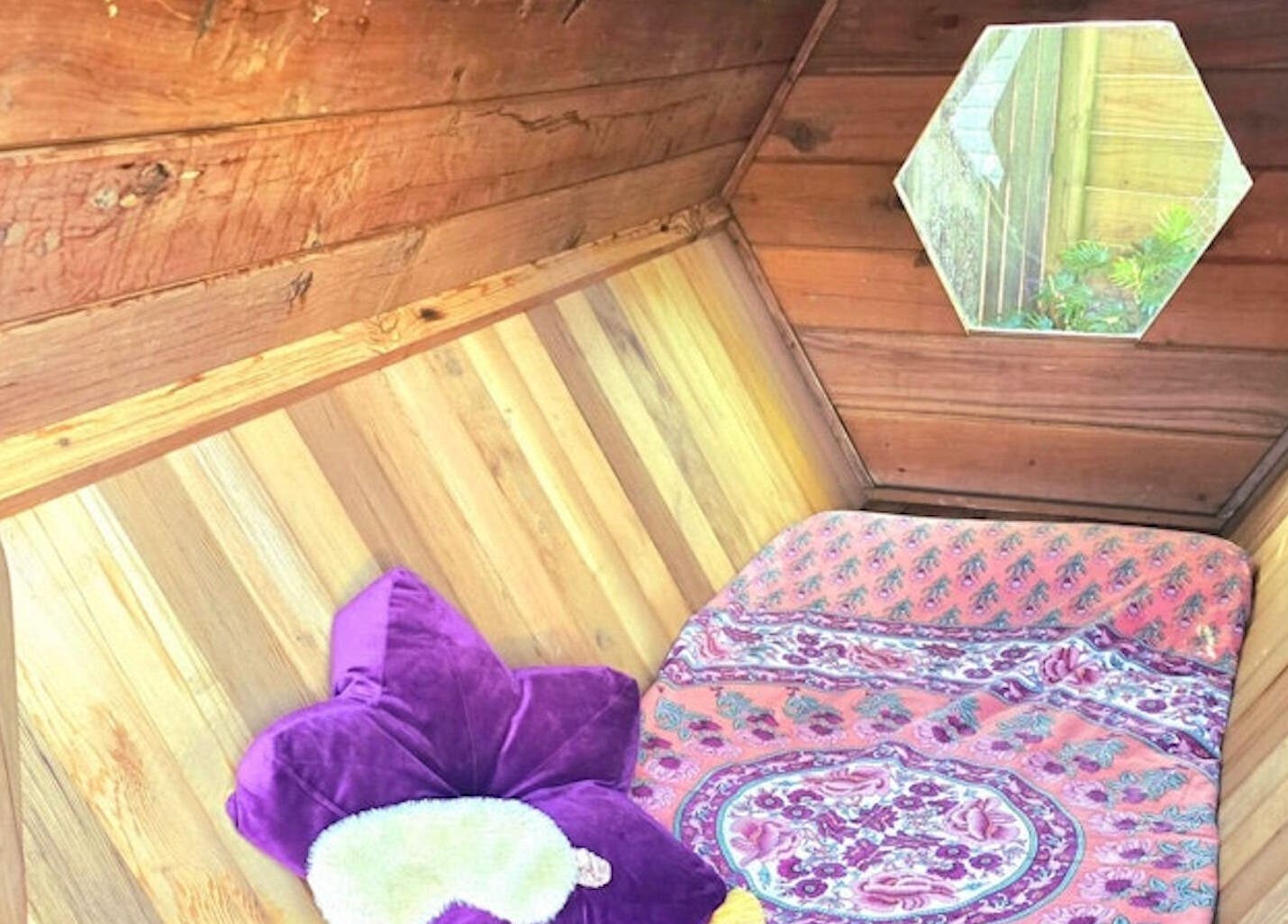 Cozy hexagonal wooden room at Bee Alive, Mullumbimby, New South Wales, AU, with vibrant cushions and decor.