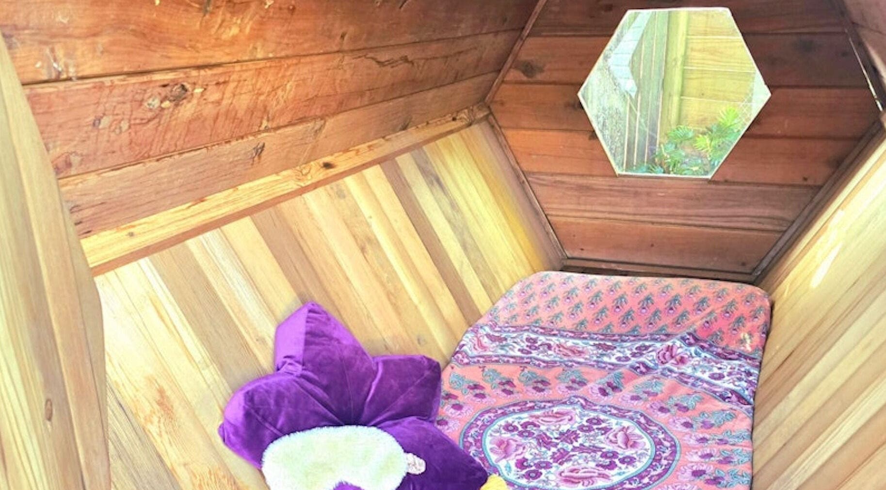 Cozy hexagonal wooden room at Bee Alive, Mullumbimby, New South Wales, AU, with vibrant cushions and decor.